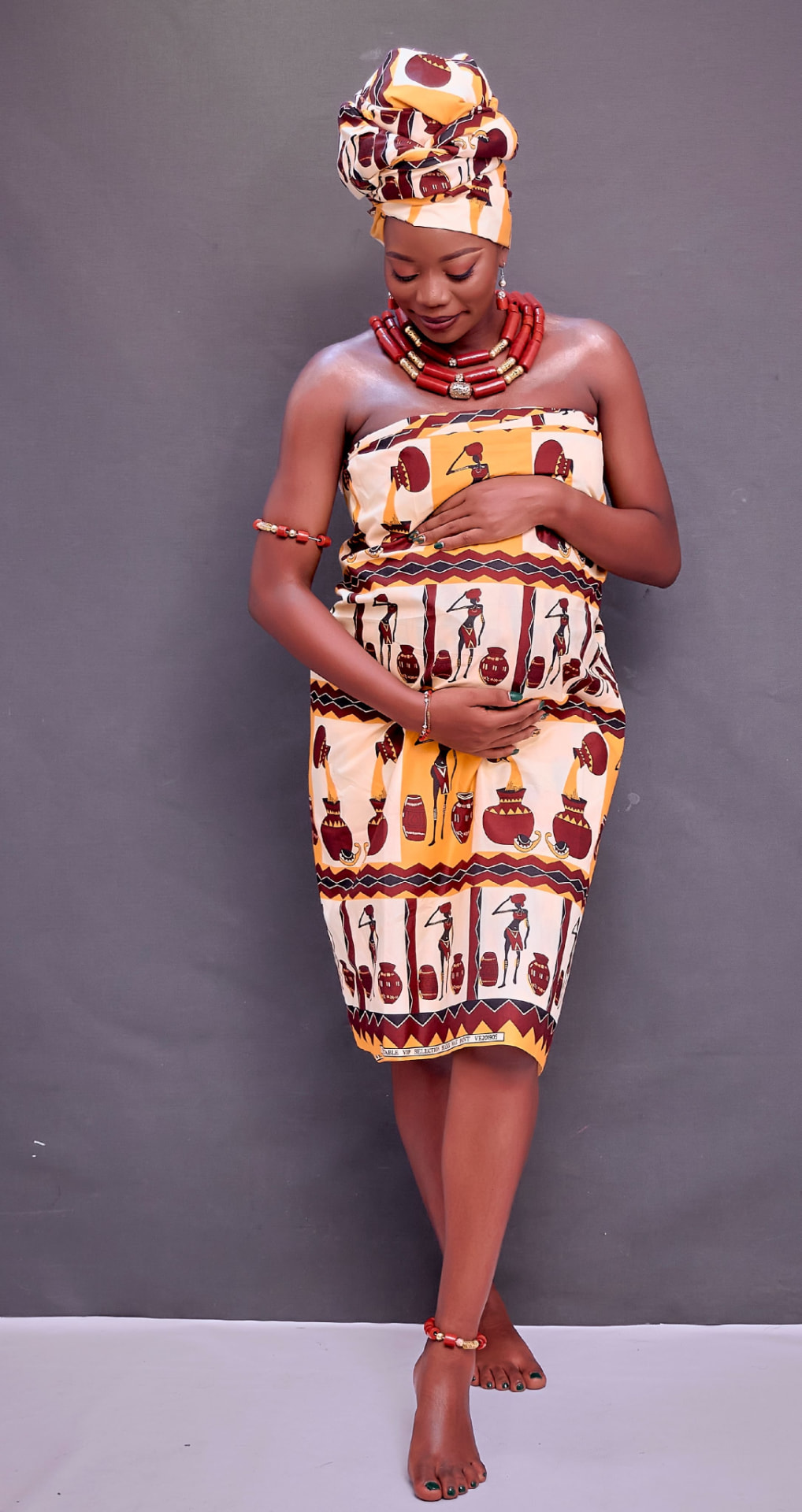 An expectant Kenyan mother in traditional dress holding her baby bump